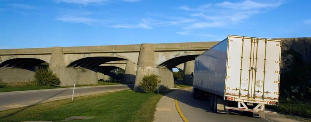 A semi truck drives under an overpass