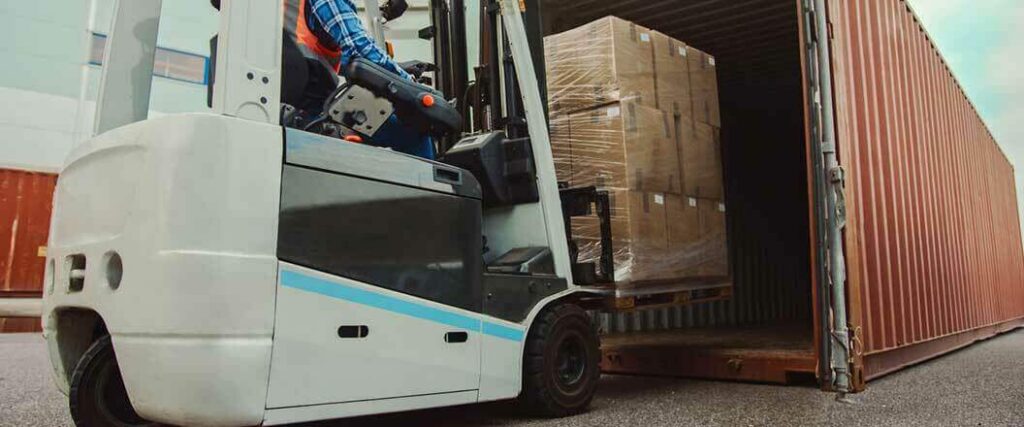 A forklift moving a palletized shipment of freight into a cargo container